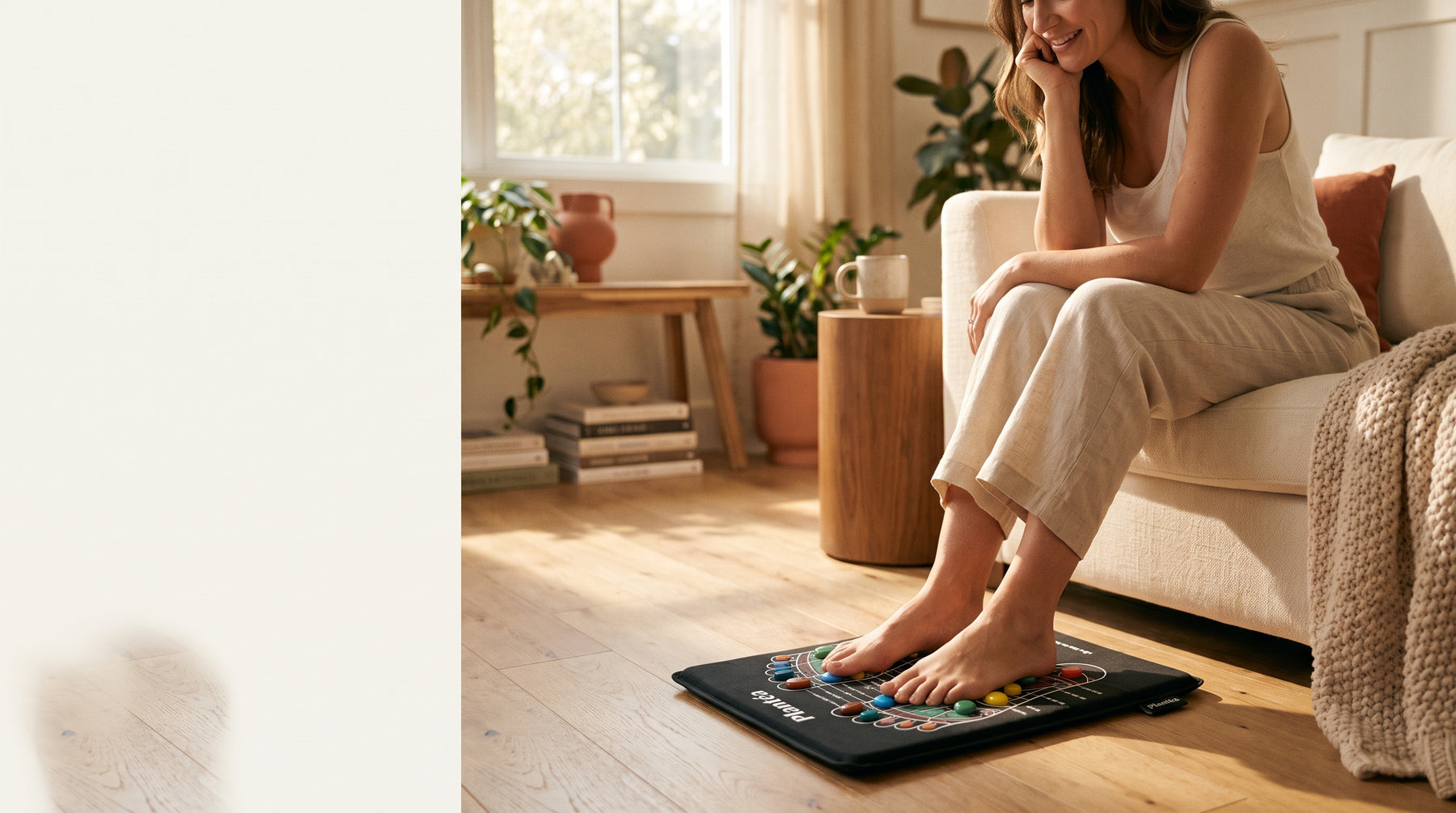Une femme assise sur son canapé, pieds nus posés sur le tapis d'acupression Plantéa noir aux pierres colorées, dans un salon lumineux